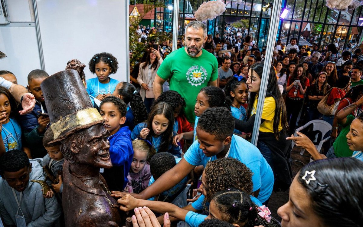 Crianças da Pequena Tribo, de camiseta azul, em volta da escultura de chocolate no Palácio de Cristal.